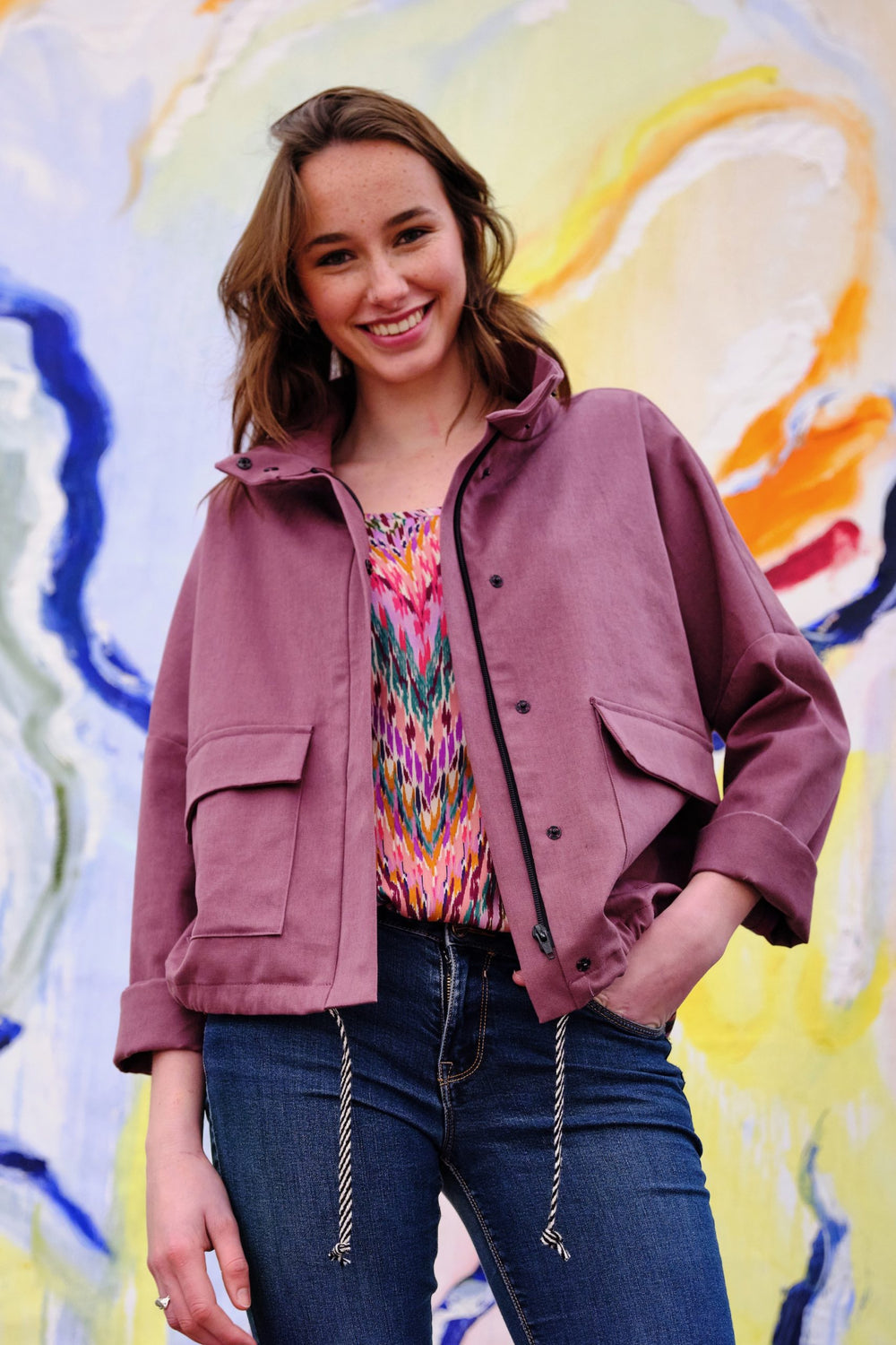 Woman wearing the Grace Jacket sewing pattern from Atelier Jupe on The Fold Line. A jacket pattern made in cotton, denim or linen fabrics, featuring drop shoulders, long sleeves, straight standing collar, front zipper hidden by placket with snap buttons, 