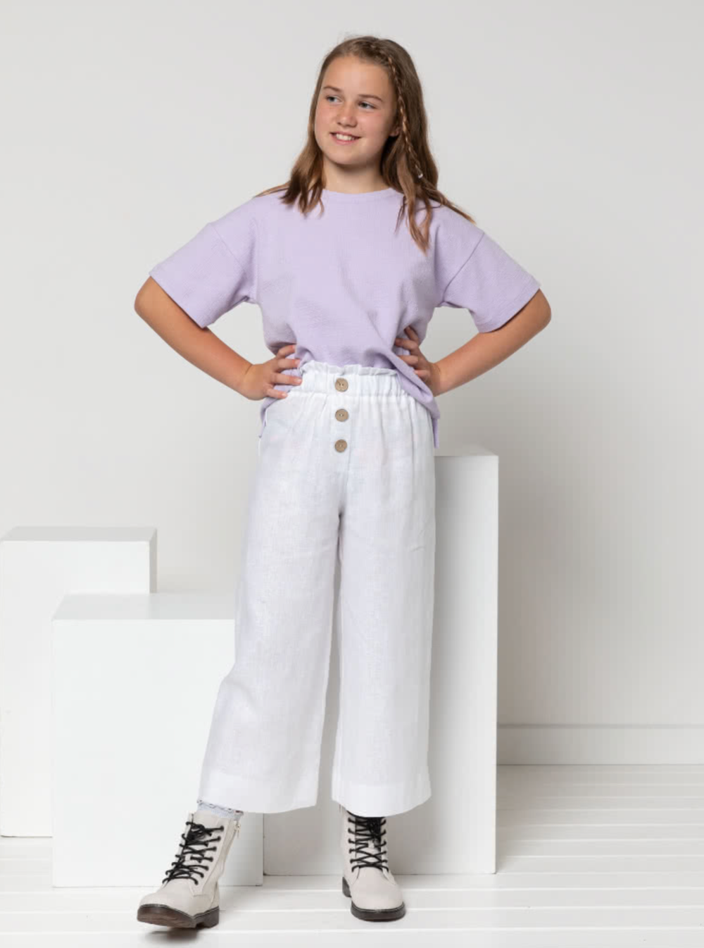 Child wearing the Child/Teen Hayden Tee sewing pattern from Style Arc on The Fold Line. A T-shirt pattern made in T-shirt fabric, jersey or light rugby fabrics, featuring a boxy silhouette, crew neck, dropped shoulder, short sleeves, and high-low hem with