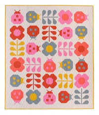 Photo showing the Hello Spring Quilt sewing pattern from Pen and Paper Patterns on The Fold Line. A quilt pattern made in quilting cotton fabrics, featuring ladybugs and flowers in pink, red, blue and yellow colours on a cream background.