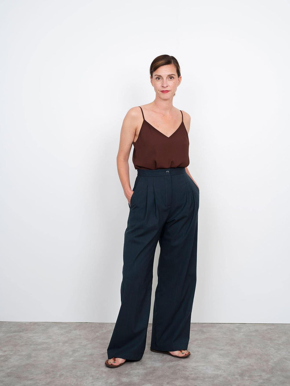 Woman wearing the High-Waisted Trousers sewing pattern from The Assembly Line on The Fold Line. A trouser pattern made in light to medium weight fabrics such as stretch wool, featuring a fitted high waist, straight waistband, fly zip, wide legs, slant fro