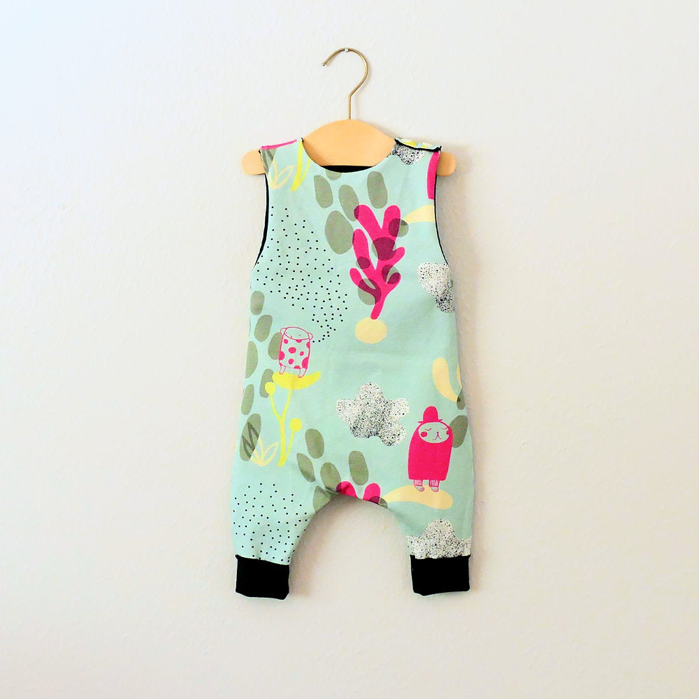 Image showing the Baby/Child Hipster Romper sewing pattern from Elemeno Patterns on The Fold Line. A sleeveless playsuit/romper pattern made in cotton knit fabrics, featuring a round neck, button shoulder fastenings and full length legs with deep ribbed h