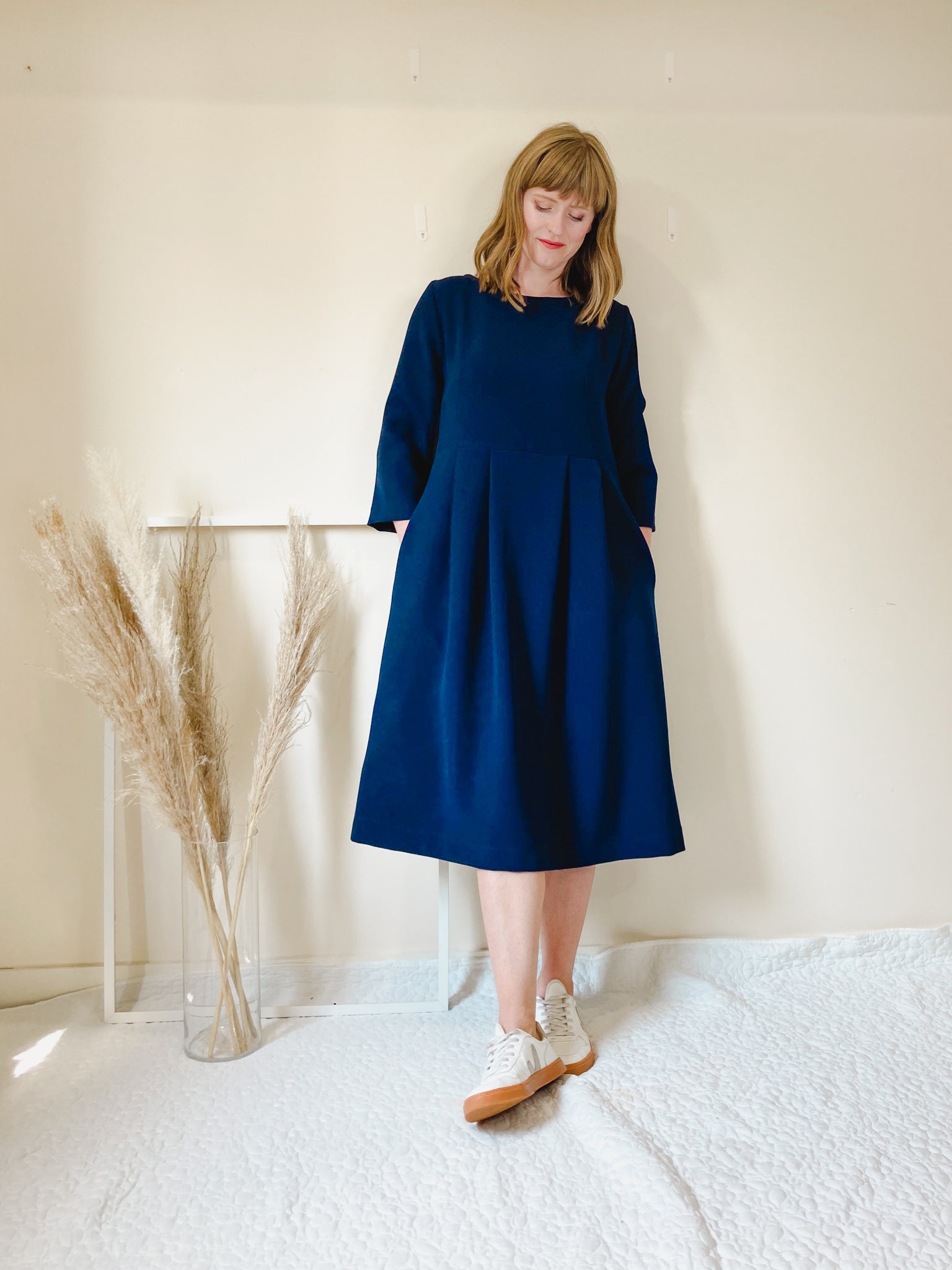 Woman wearing the Cissy Dress sewing pattern from Homer and Howells on The Fold Line. A dress pattern made in cottons, cords, wool or crepe fabrics, featuring a midi length, boxy fit, boat neck, bracelet length sleeves, centre back zip and side seam pocke