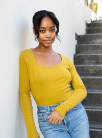 Woman wearing the Honeygirl Tee sewing pattern from Paradise Patterns on The Fold Line. A T-shirt pattern made in cotton pointelles fabrics, featuring a fitted style, long sleeves, scoop neck, and hip length hem.