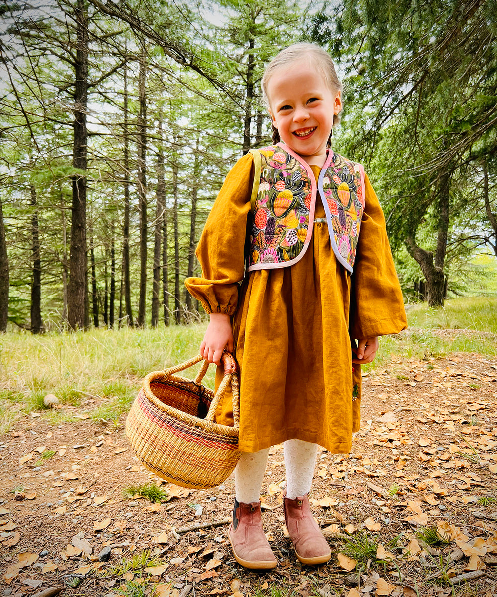 Child wearing the Honu Vest (Quilted) sewing pattern from Below the Kōwhai on The Fold Line. A quilted vest pattern made in quilting cotton, linen, drill, canvas or furnishing fabrics, featuring a single hook and eye closure, and curved hems with bias bou