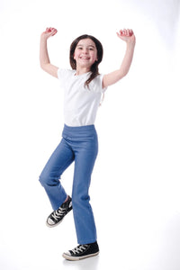 Girl wearing the Child/Teen Hopper Trousers sewing pattern from Little Rosy Cheeks on The Fold Line. A pull-on trouser pattern made in Ponte Roma, French terry, loop back jersey, or stretch denim fabric, featuring a kick flare, elasticated waist, and pock