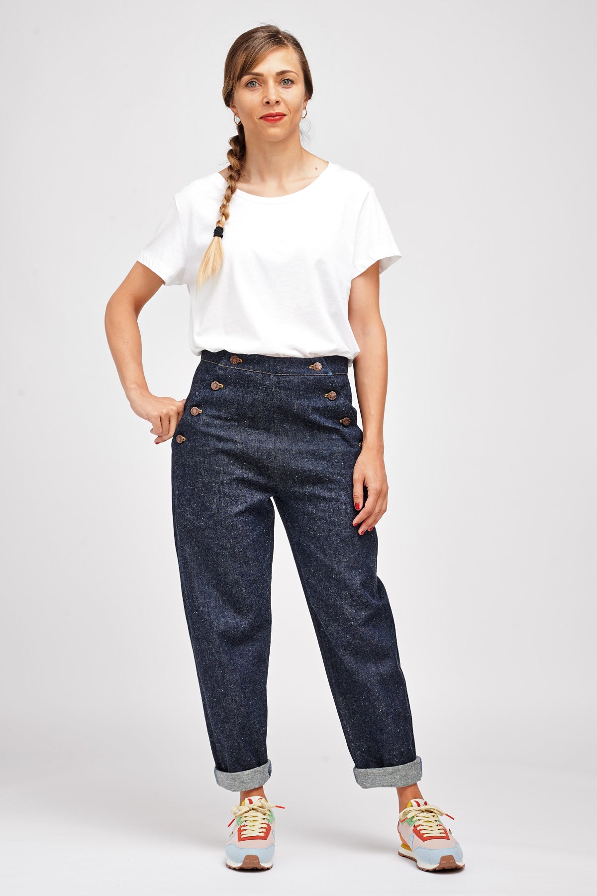Woman wearing the Nout Trousers sewing pattern from I AM Patterns on The Fold Line. A sailor trouser pattern made in denim, cotton twill, chambray, linen, jacquard, corduroy or gabardine fabrics, featuring an ankle length, tapered leg, buttoned front flap