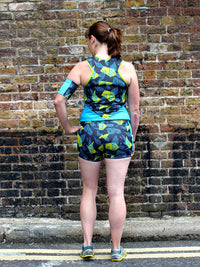 Woman wearing the VNA Top sewing pattern from Fehr Trade on The Fold Line. A sports top pattern made in Lycra Jersey fabrics, featuring a close-fit, sleeveless, front V-neck, curved under bust seam, angular seaming in the back, bound neckline and armhole 