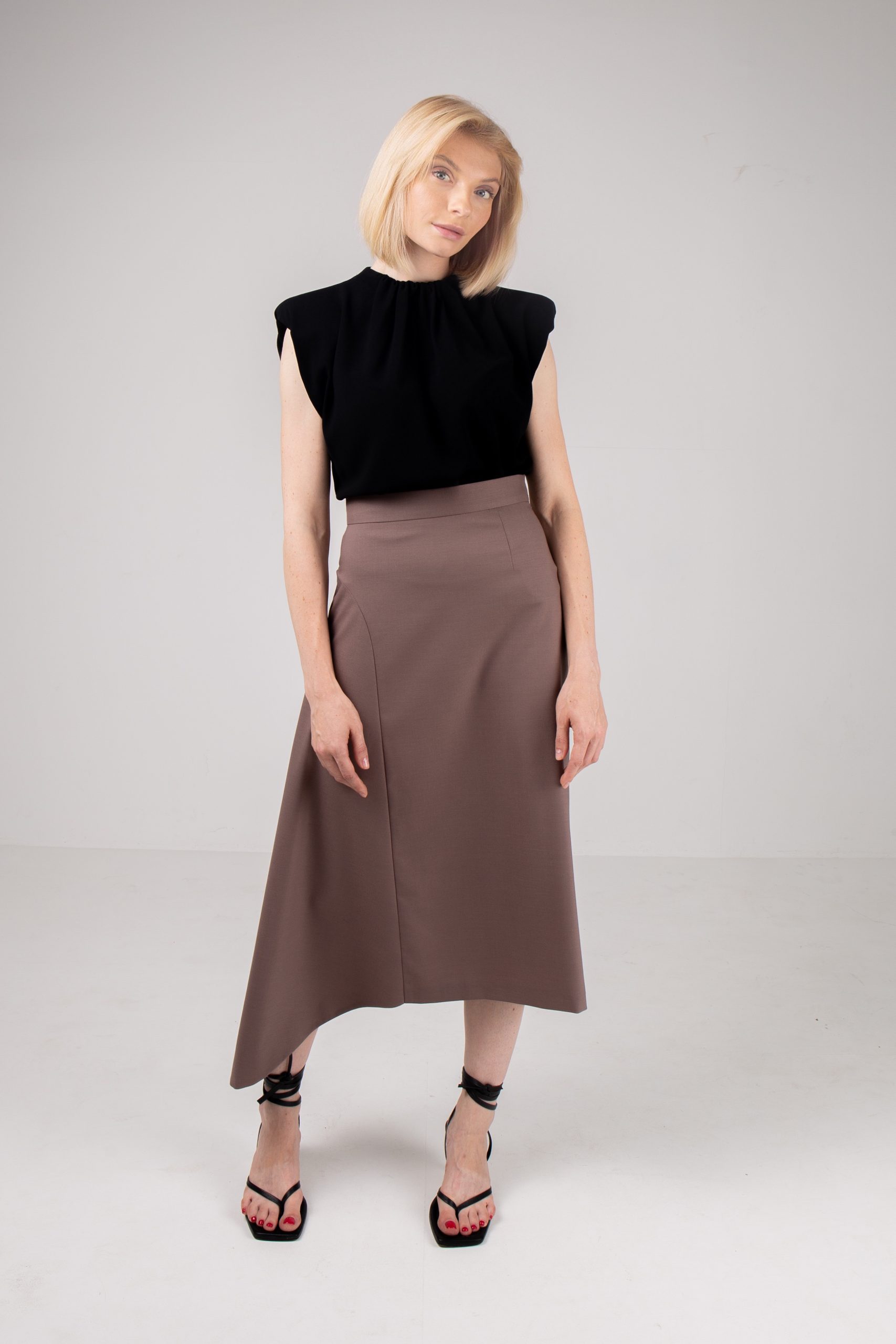 Woman wearing the Cecile Skirt sewing pattern by Vikisews. An asymmetrical, semi-fitted, lined skirt pattern made in wool, gabardine, viscose crepe, silk velvet, silk or modal fabrics, featuring a straight silhouette on the left side and a flared insert o