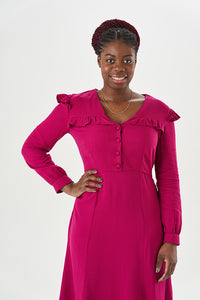 Woman wearing the Isla Dress sewing pattern from Sew Over It on The Fold Line. A dress pattern made in rayon, viscos or crepe fabrics, featuring a button-up bodice, bust and waist darts, yoke with front frill, shoulders frill, long set-in sleeves with gat