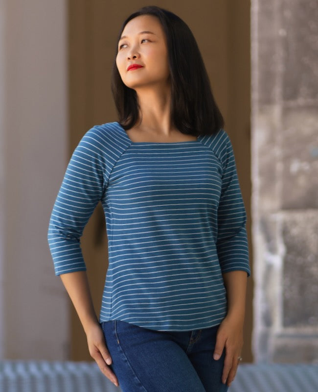 Woman wearing the Islares Top sewing pattern from Itch to Stitch on The Fold Line. A knit top pattern made in jersey, interlock, viscose French terry and double-brushed poly fabrics, featuring a square neck, 3/4 raglan sleeves, shoulder darts, curved heml