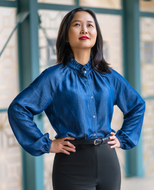 Woman wearing the Majorelle Shirt sewing pattern from Itch to Stitch on The Fold Line. A blouse pattern made in viscose/rayon challis, voile, batiste, broadcloth and chambray fabrics, featuring a gathered neckline with ruffled collar, centre front snap cl