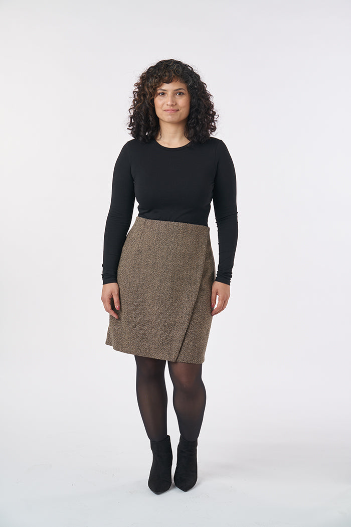 Woman wearing the Ivy Skirt sewing pattern from Sew Over It on The Fold Line. A skirt pattern made in cotton, stretch cotton, denim, wool suiting, or melton wool fabric, featuring an asymmetrical faux wrap front, natural waist, front and back darts, facin
