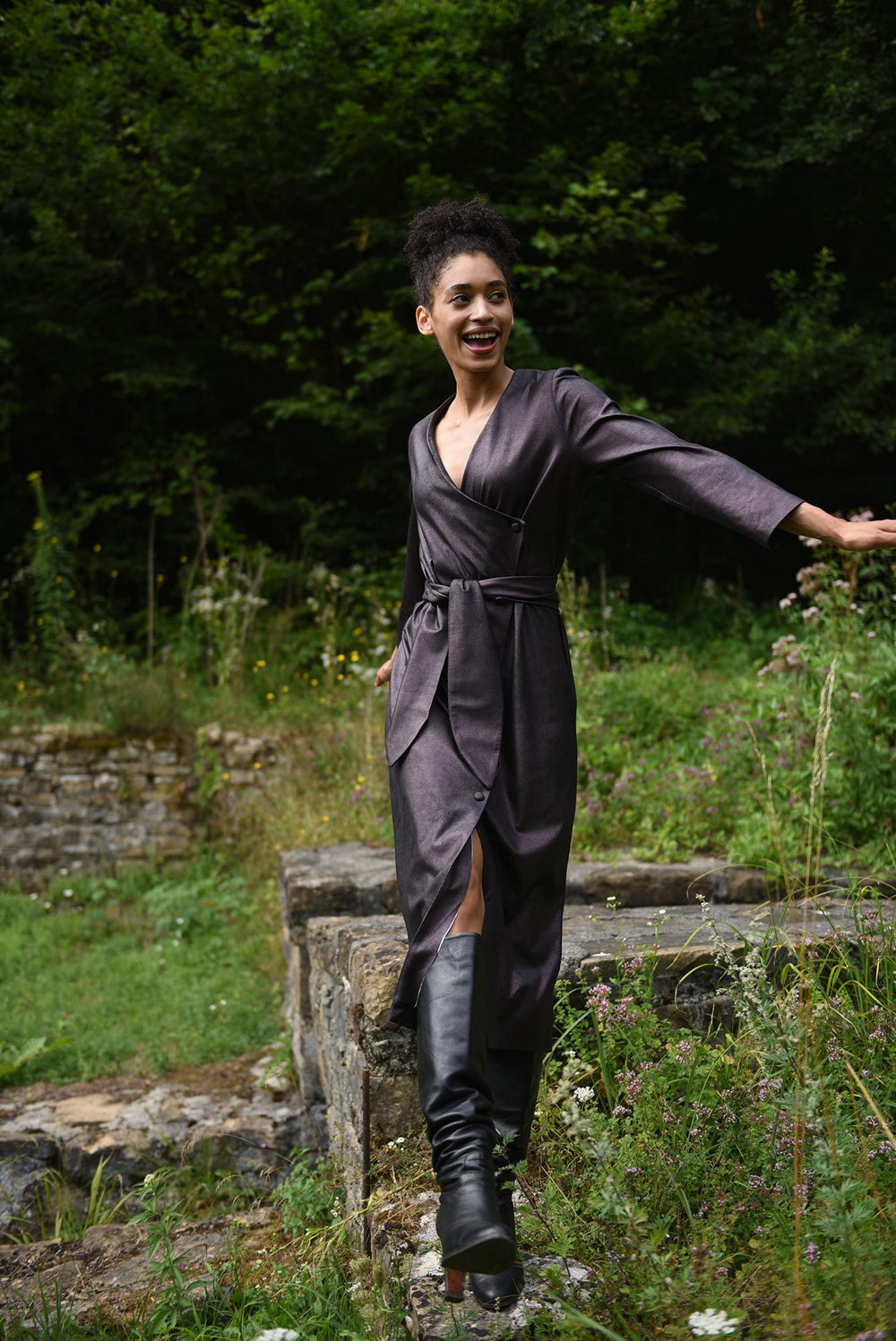 Woman wearing the Izzy Dress sewing pattern from Fibre Mood on The Fold Line. A wrap dress pattern made in knit and woven fabrics, featuring a slanted button closure, V-neckline, loose wide self-belt, long straight sleeves, midi length and a V shaped fron