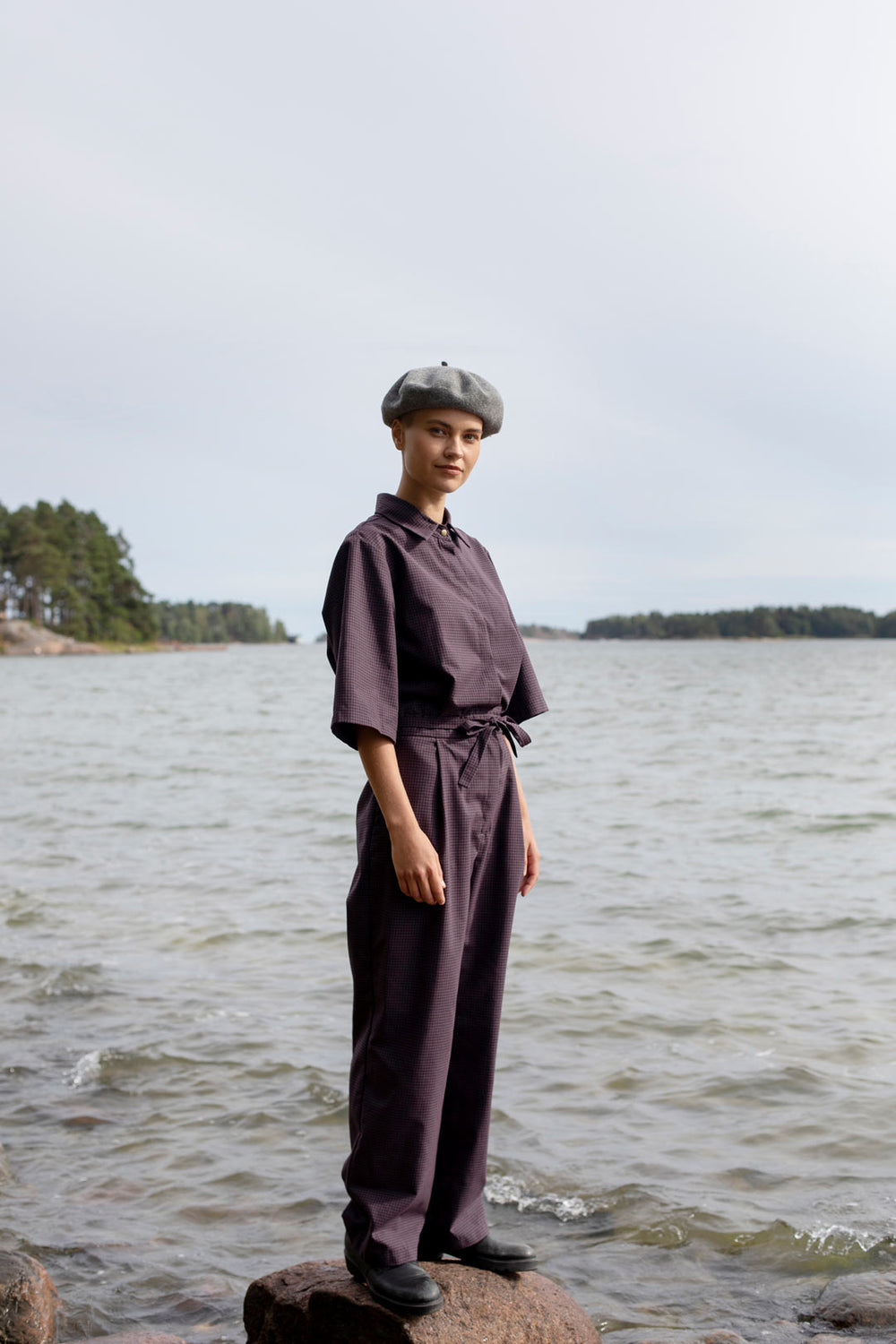 Woman wearing the Judith Jumpsuit sewing pattern from TAUKO on The Fold Line. A jumpsuit pattern made in cotton, cotton/polyester blend, linen, hemp, or light denim fabrics, featuring a pointed collar, snap button placket, side pockets, self-fabric belt, 