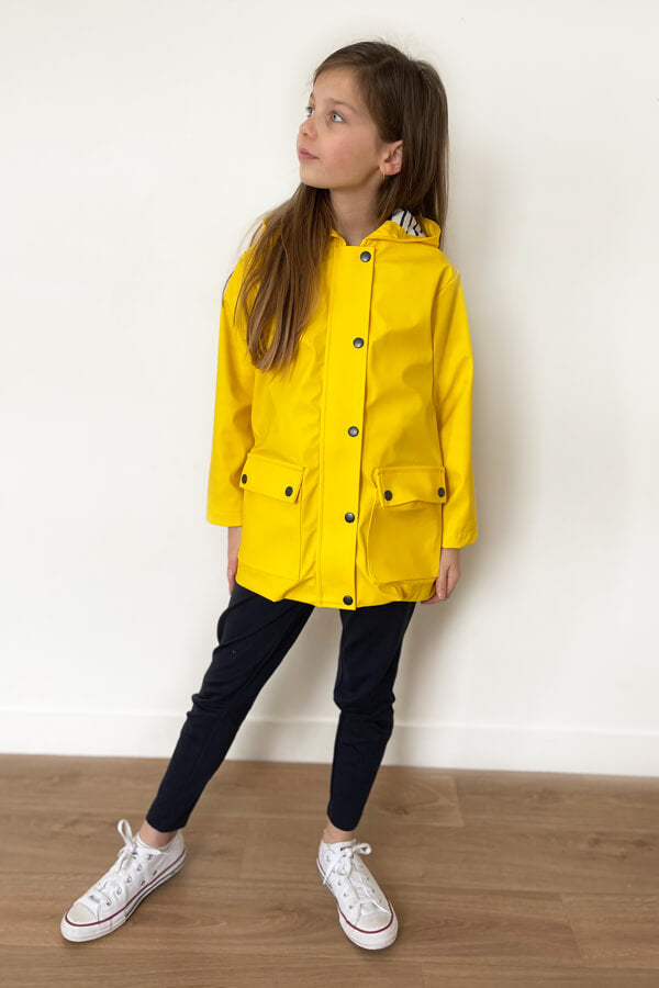 Child wearing the Child/Teen Mini Jacques Raincoat sewing pattern from I AM Patterns on The Fold Line. A raincoat pattern made in water-resistant and waterproof fabrics, gabardine, waxed cotton, wool coating, cotton serge, cotton twill, denim or corduroy 