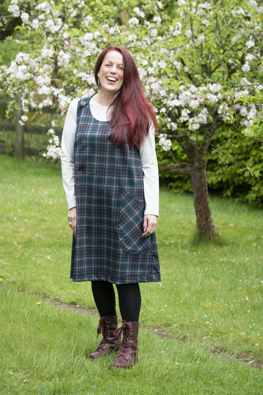 Woman wearing the Jayne Pinafore Dress sewing pattern from Bobbins and Buttons on The Fold Line. A dress pattern made in linen, medium weight denim or medium weight cotton fabrics, featuring an A-line silhouette, no zip, buttons at the shoulders, patch po