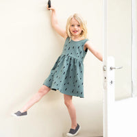 Child wearing the Child/Teen Jente Dress sewing pattern from Itch to Stitch on The Fold Line. A sleeveless dress pattern made in stretch fabrics such as tencel or bamboo jersey, featuring a gathered skirt, overlapping back panels with a low cut and boat n