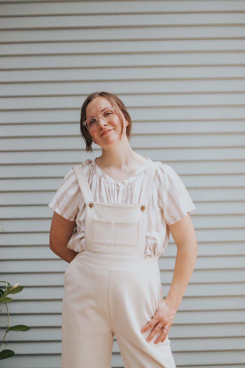 Woman wearing the Jordan Overalls sewing pattern from Madswick on The Fold Line. A dungaree pattern made in wool blends, linen, duck canvas, cotton twill, or denim fabrics, featuring a cropped bib with pockets, high waist, elasticated back waistband, back