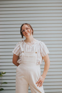 Woman wearing the Jordan Overalls sewing pattern from Madswick on The Fold Line. A dungaree pattern made in wool blends, linen, duck canvas, cotton twill, or denim fabrics, featuring a cropped bib with pockets, high waist, elasticated back waistband, back