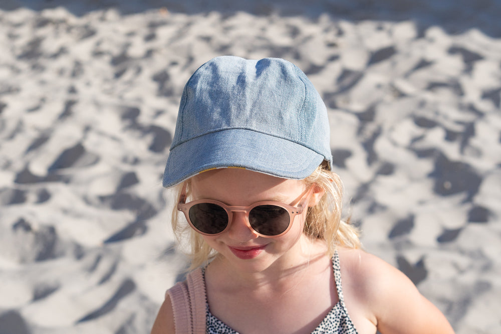 Child wearing the Baby/Child/Adult Jua Cap sewing pattern from WISJ Designs on The Fold Line. A cap pattern made in cotton or canvas fabrics, featuring four panels, visor, elastic strap at back, reversible, and fully lined.