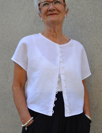 Woman wearing the Judy Top sewing pattern by Tessuti Fabrics. A top pattern made in light to medium weight linen and cottons, textured cottons and wool crepe fabrics, featuring a multi-button rouleau detail, drop shoulders, and a curved hemline that sits 