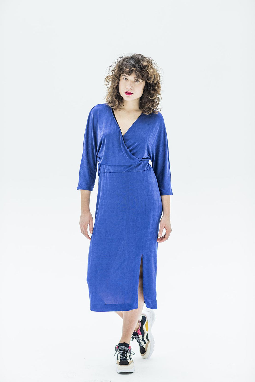 Woman wearing the Juliette Dress sewing pattern from Fibre Mood on The Fold Line. A wrap dress pattern made in Jersey fabrics, featuring an open slit at the front hem, elasticated waistband, ¾ length sleeves, V-neck and midi length.