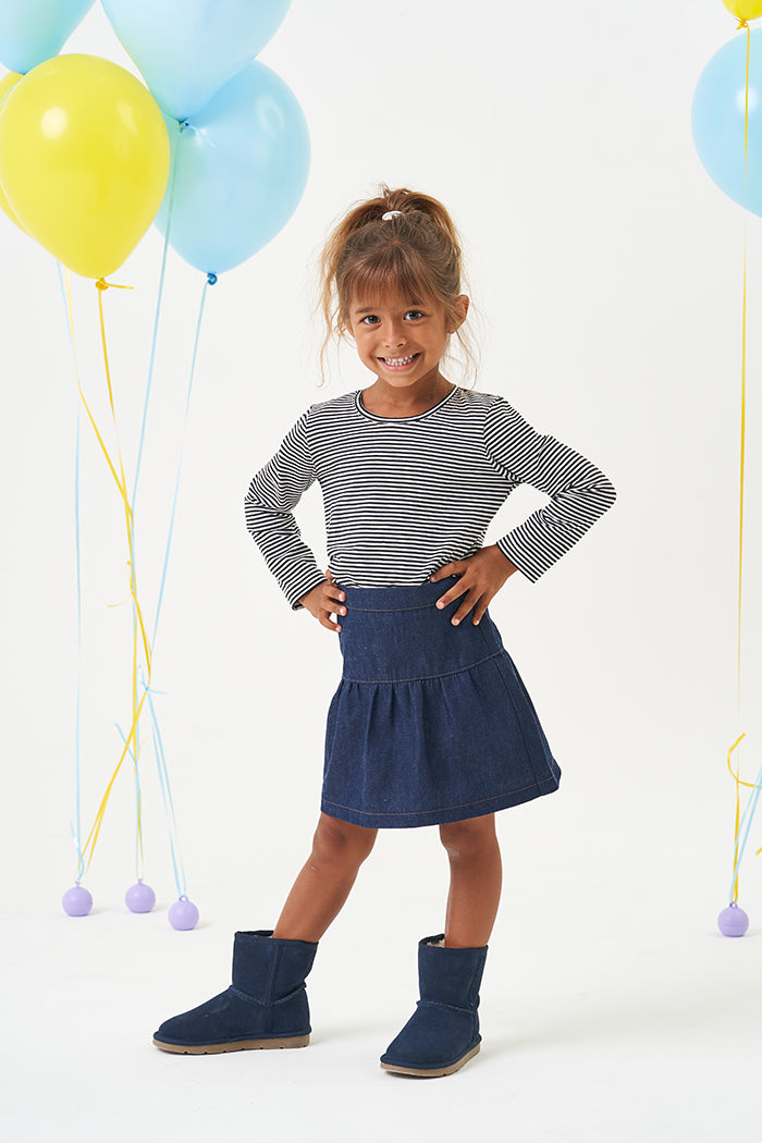 Child wearing the Baby/Child Juniper Skirt sewing pattern from Poppy & Jazz on The Fold Line. A skirt pattern made in cotton lawn, cotton poplin, linen, denim, quilting cottons or corduroy fabrics, featuring a flat front waistband with elastic at the back
