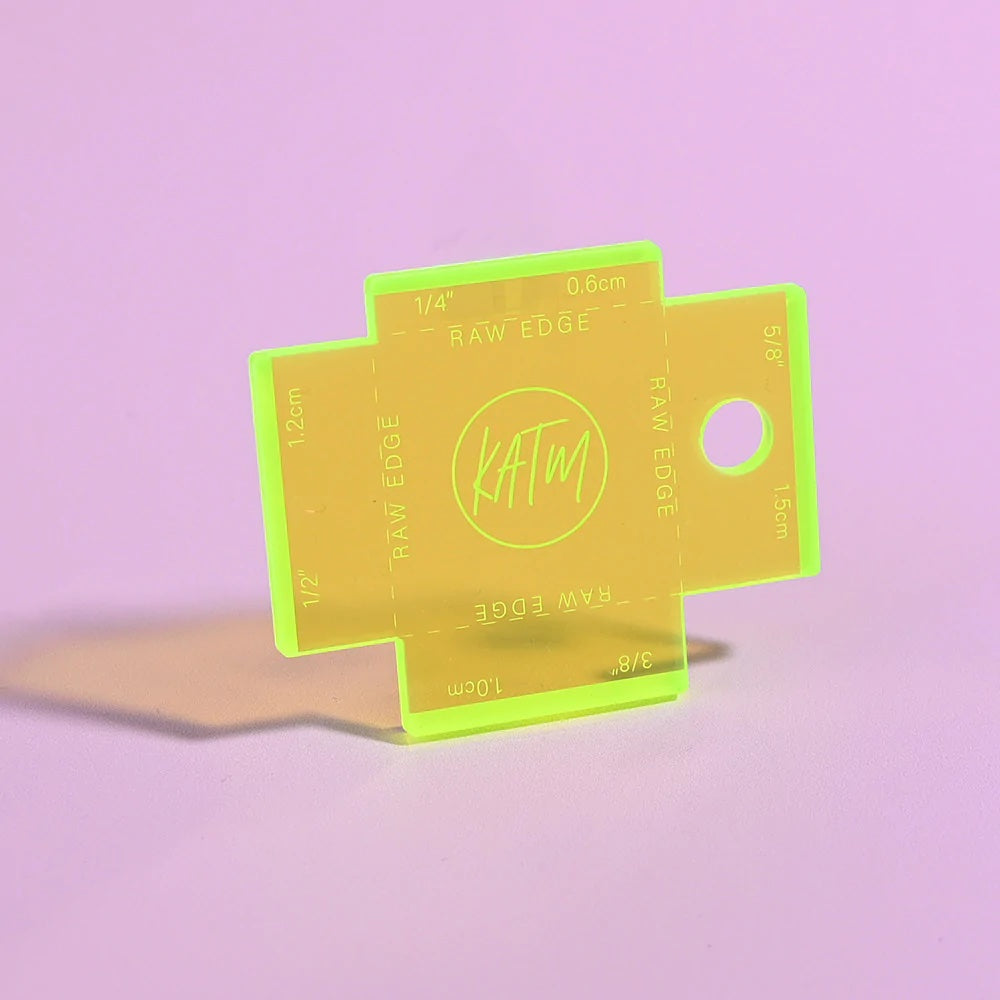 Photo showing the Label Gauge from Kylie & The Machine on The Fold Line. This fluorescent yellow acrylic gauge with laser etched measurements will help you to position your label perfectly with the four most common seam allowances.