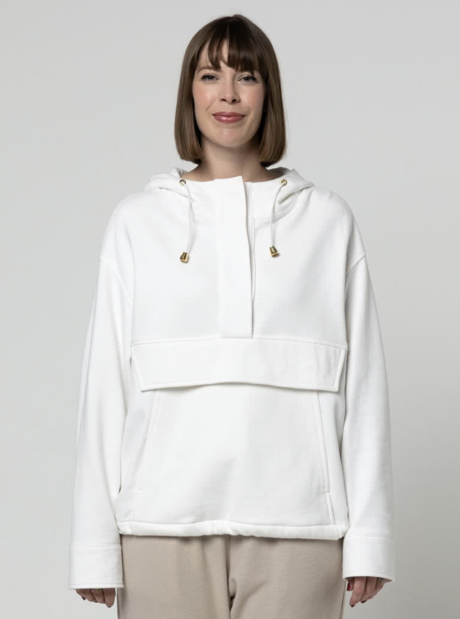 Woman wearing the Kennedy Hooded Top sewing pattern from Style Arc on The Fold Line. A hooded top pattern made in sweater knit, rugby knit, tencel or fine wool fabrics, featuring a front kangaroo pocket with flap, hood with drawstring, half placket with s