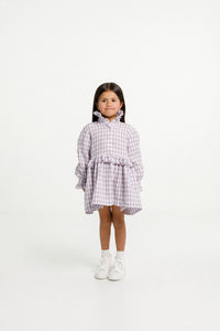 Child wearing the Ashling Dress sewing pattern from Papercut Patterns on The Fold Line. A dress pattern made in cotton, linen, silk, rayon or blends fabrics, featuring just above knee length, long sleeve with gathered cuffs, ruffle collar and waist, butto