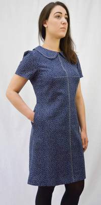 Woman wearing the Kitty Dress sewing pattern from Maven Patterns on The Fold Line. A semi-fitted dress pattern made in denim, chambray, linen, cotton twill or fine wool fabric, featuring statement bust darts, a peter pan collar, short gathered sleeves, in