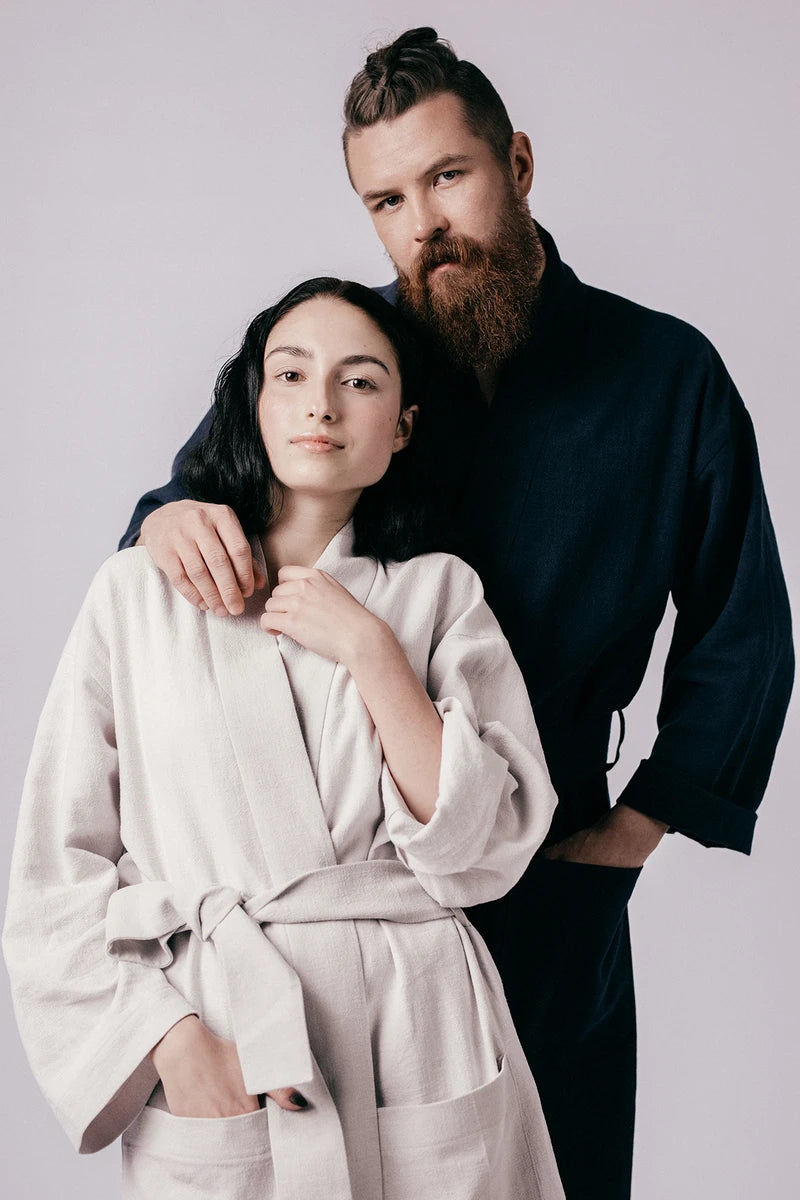Woman and Man wearing the Lahja Unisex Dressing Gown sewing pattern from Named on The Fold Line. A dressing gown pattern made in linen, terry cloth, honeycomb, rayon or satin fabrics, featuring knee or midi length, cropped or full-length sleeves, large pa