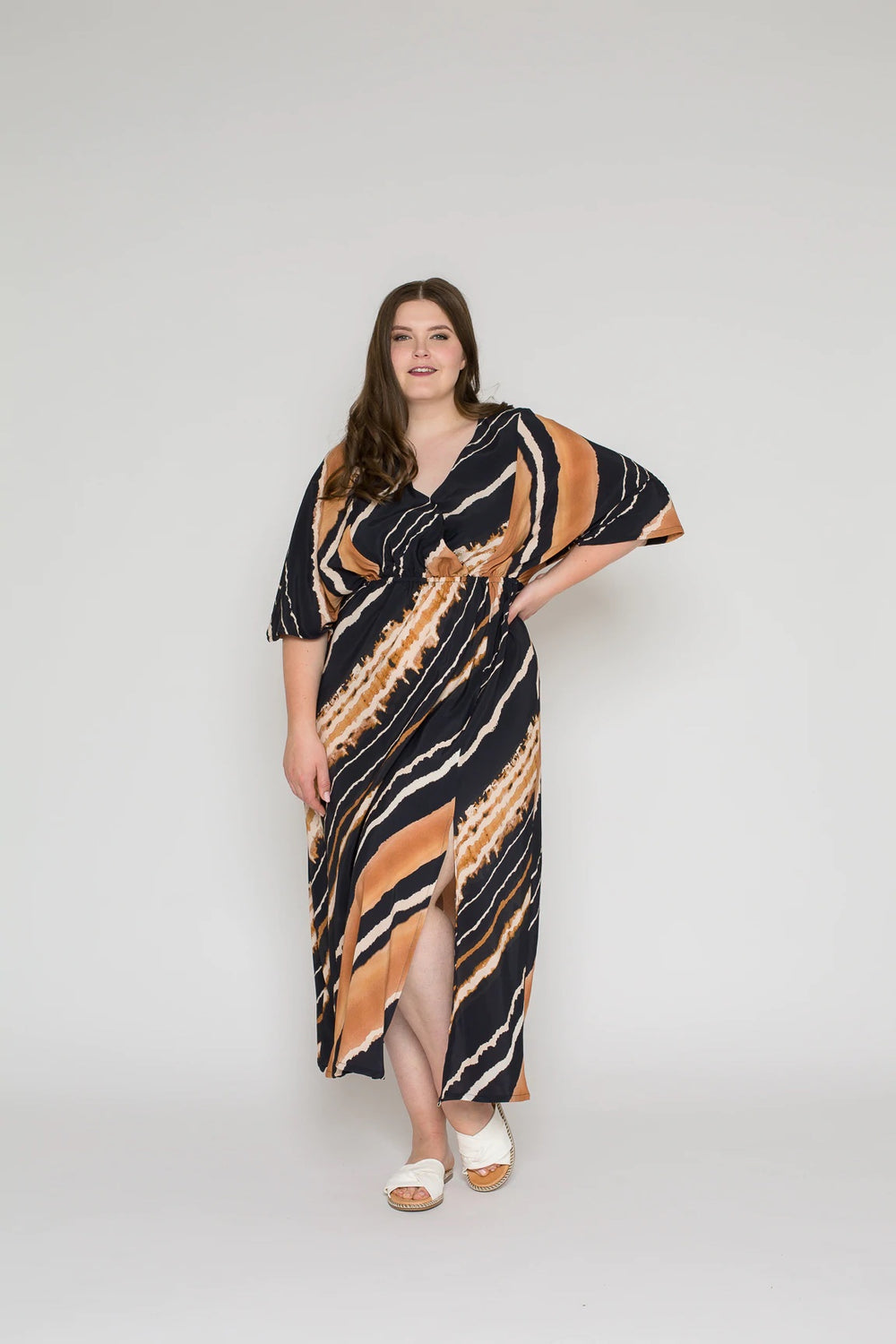 Woman wearing the Leana Caftan sewing pattern from Bara Studio on The Fold Line. A dress pattern made in viscose, cotton, linen or tencel fabrics, featuring a relaxed fit, elasticated waist, wide mid-length sleeves, front slit, V-neck and midi length.