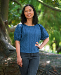 Woman wearing the Lemont Top sewing pattern from Itch to Stitch on The Fold Line. A top pattern made in shirting, rayon challis, chambray or lightweight linen fabrics, featuring short dolman sleeves, no buttons or zip, narrow shoulders and puffy sleeve he