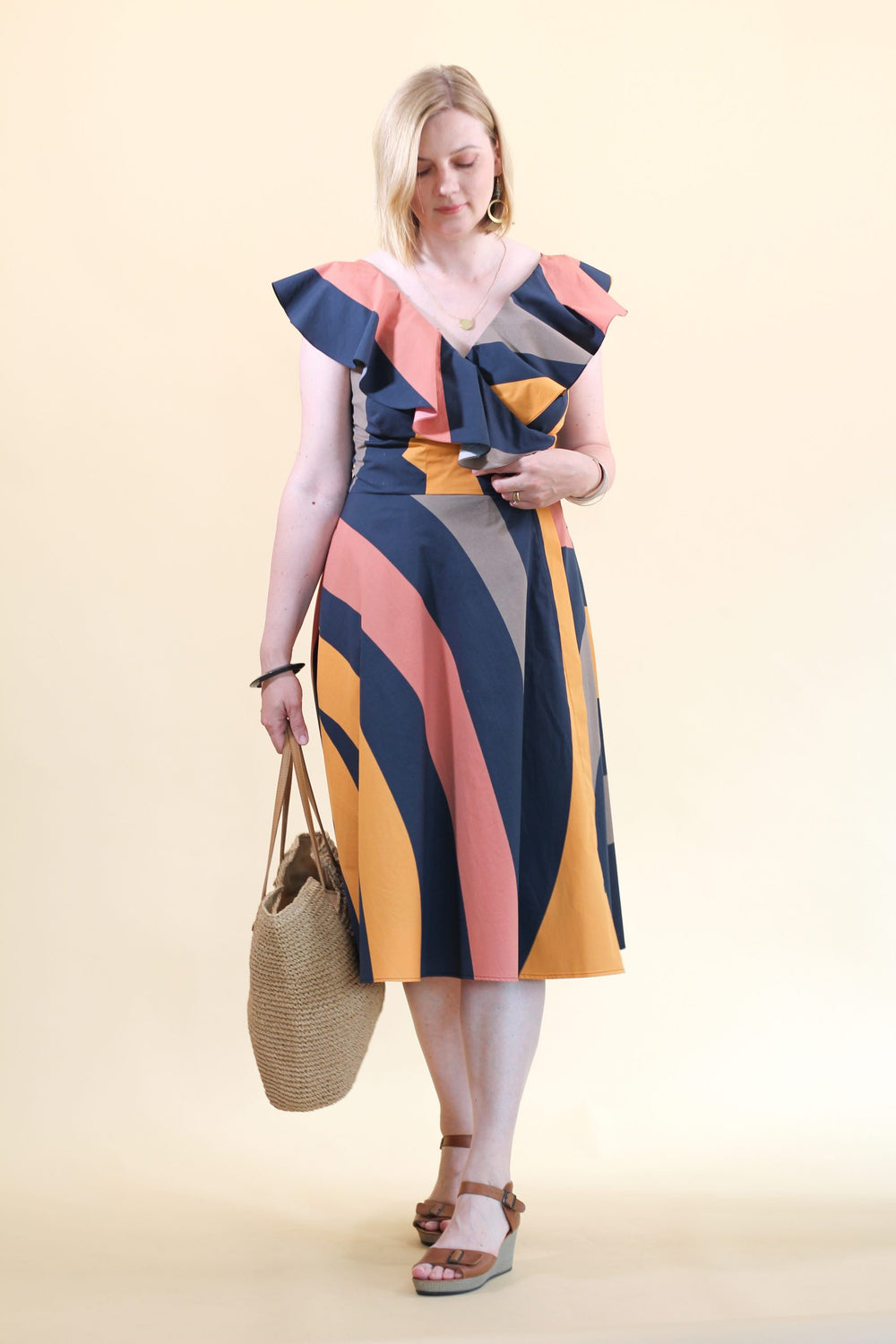 Woman wearing Lessya Dress sewing pattern from Lenaline Patterns on The Fold Line. A wrap dress pattern made in cotton, linen, tencel, cotton poplin, cotton twill or denim fabrics, featuring a fitted bodice, deep V-neck, full bias skirt, shoulder ruffles,