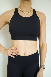 Woman wearing the Lia Sports Bra sewing pattern from Bara Studio on The Fold Line. A sports bra pattern made in Bi-stretch fabrics, featuring a racer back, and elastic underband.
