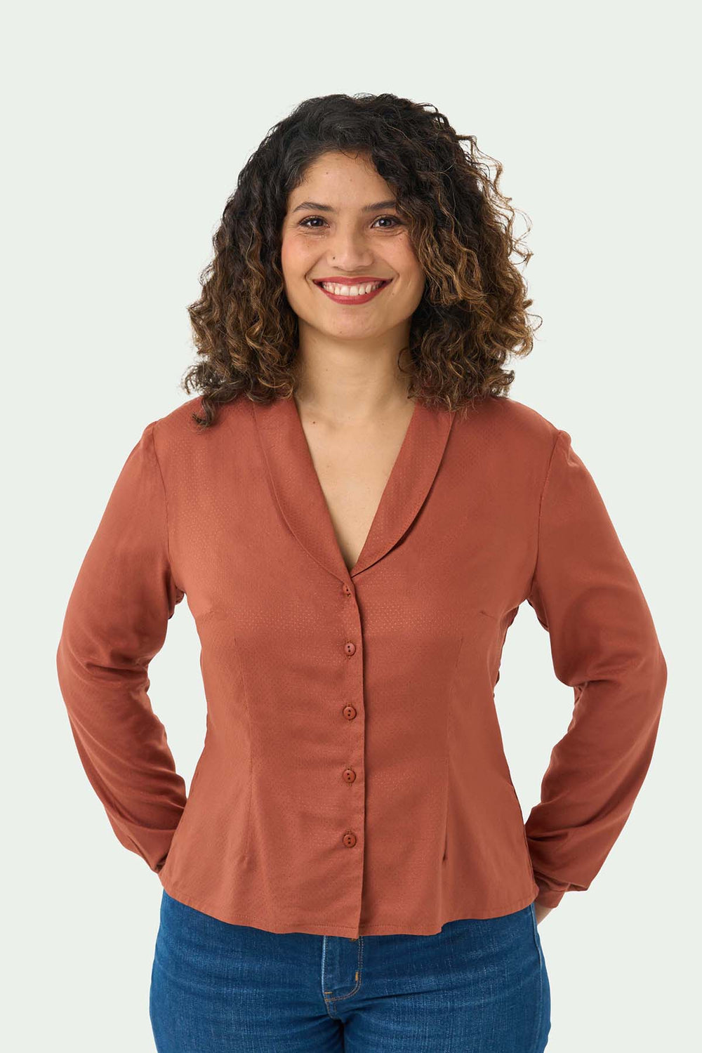 Woman wearing the Lilian Blouse sewing pattern from Sew Over It on The Fold Line. A blouse pattern made in rayon, viscose or crepe fabrics, featuring a button front, shawl collar, full length sleeves with narrow cuff, V-neck, front and back double-ended d