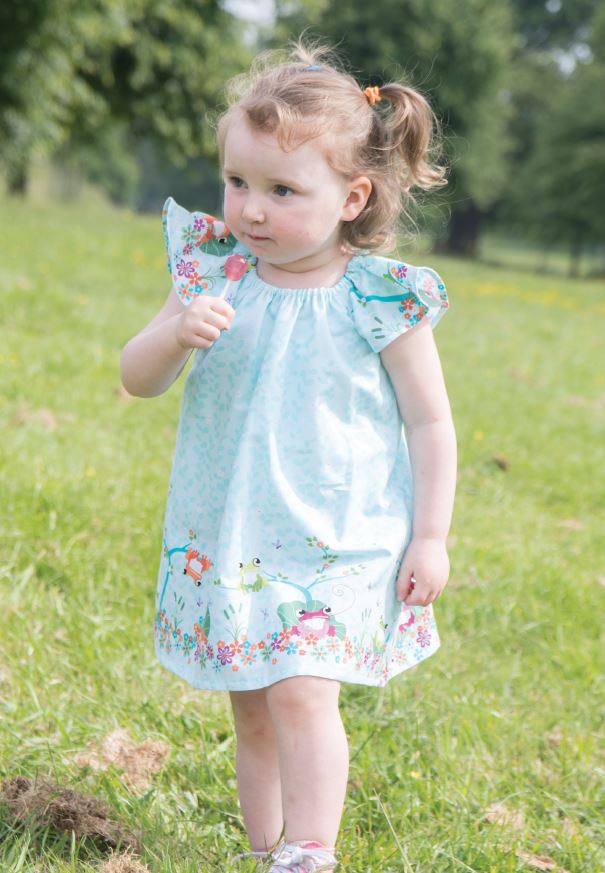 Child wearing the Baby/Child Lillia Rae Dress sewing pattern by Bobbins and Buttons. A dress pattern made in cotton and cotton blends, broadcloth or cotton lawn fabrics, featuring a loose fit, flutter sleeves and elastic neckline.