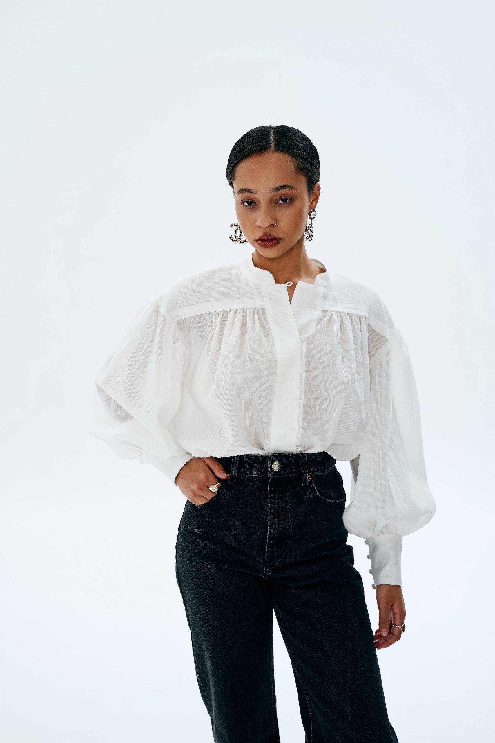 Woman wearing the Lisa Blouse sewing pattern from Vikisews on The Fold Line. An blouse pattern made in gauze, textured viscose, silk, artificial silk, chiffon, batiste, or organza fabrics, featuring a straight-cut, front and back yokes with gathers, wide 