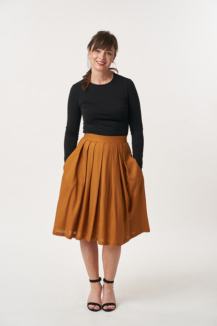 Woman wearing the Lizzie Skirt sewing pattern from Sew Over It on The Fold Line. A pleated skirt pattern made in cotton, wools and soft furnishing fabrics, featuring a full lining, waistband, concealed zip, in-seam pockets, front and back pleats, knee-len