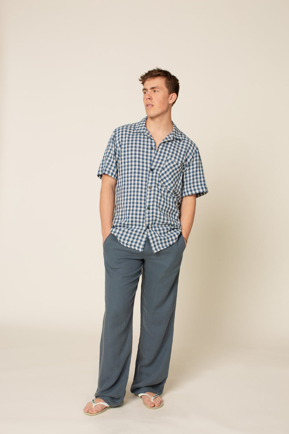Man wearing the Men's Loose Linen Pants sewing pattern from Wardrobe by Me on The Fold Line. A trouser pattern made in linen, cotton or viscose fabrics, featuring an elasticated waist with drawstring, in-seam side pockets, back patch pocket, and relaxed f
