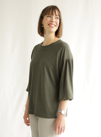 Woman wearing the Lorna Knit Top sewing pattern from Style Arc on The Fold Line. A knit top pattern made in jersey or cotton knit fabrics, featuring a hip-length, crew neck, front and back yokes, dropped shoulder, 3/4-length raglan sleeves with slight gat