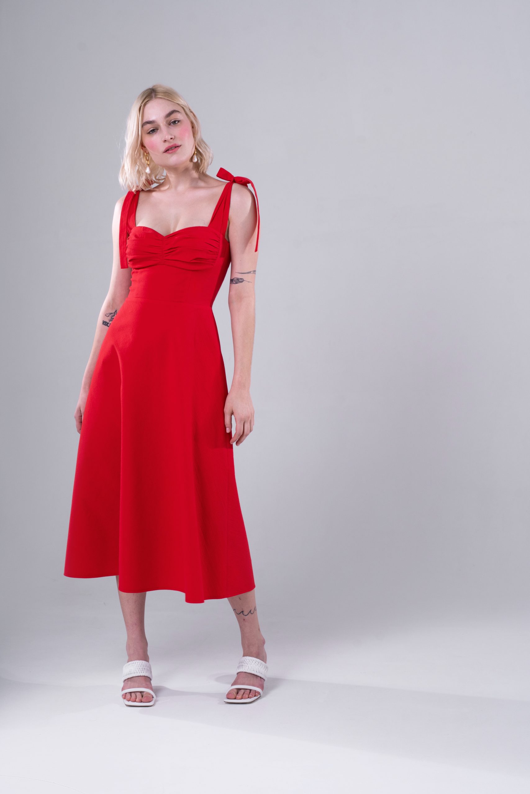 Woman wearing the Lorraine Dress sewing pattern from Vikisews on The Fold Line. A slip dress pattern made in satin, viscose, stretch crepe, linen, poplin, sateen or silk fabrics, featuring a close fit, accentuated waist, tie straps, waist seam, front bodi