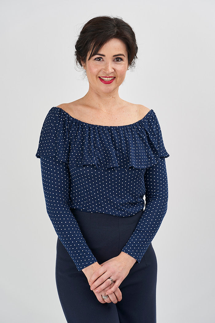 Woman wearing the Lucia Top sewing pattern from Sew Over It on The Fold Line. A top pattern made in cotton or viscose jersey fabrics, featuring an elasticated off-the-shoulder neckline, front and back neck frill and long sleeves.