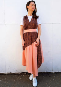 Woman wearing the Lynn Pinafore sewing pattern by Vanessa Hansen. A pinafore dress pattern made in cotton lawn, viscose challis and viscose blends, crepe de chine or charmeuse fabrics, featuring a V-neck, diagonal gathered tier, asymmetrical hem, left sid