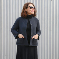 Woman wearing the Lyon Jacket sewing pattern from Tessuti on The Fold Line. A jacket pattern made in boiled wool knit or boiled felted wool fabric, featuring a semi-fit, collarless, hip length, front shoulder darts, back neck band, drop shoulders, bracele