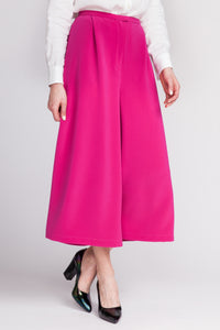 Woman wearing the Mimosa Culottes sewing pattern from Named on The Fold Line. A culottes pattern made in non-stretch trousers fabrics, featuring a midi-length, high waist, wide legs, slanted front pleats, fly front zip fastening, slash side pockets and na