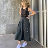 Woman wearing the Madden Skirt sewing pattern from Tessuti Fabrics on The Fold Line. A skirt pattern made in linens, linen blends, cotton, lightweight wool, tencel and silk fabrics, featuring a midi-length, pleated skirt waist, left-side button opening, c