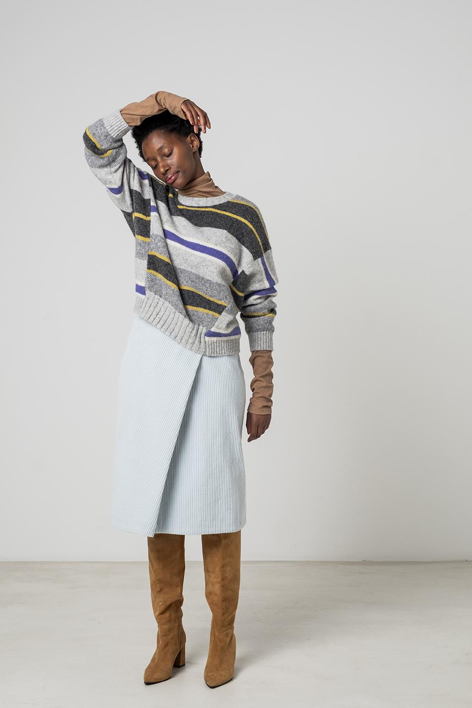 Woman wearing the Maddie Skirt sewing pattern from Fibre Mood on The Fold Line. A faux wrap skirt pattern made in wool, corduroy, denim or crepe fabrics, featuring a waistband with snap button closure and knee length hem.