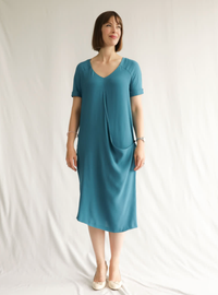 Woman wearing the Maeve Woven Dress sewing pattern from Style Arc on The Fold Line. A Dress pattern made in viscose, silk or crepe fabrics, featuring a slip-on style, V-neck, front and back yokes extending into sleeves, turn-up cuffs, inverted back pleat,